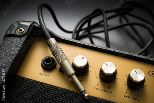 Fotografie Black guitar amplifier with jack cable on black  background