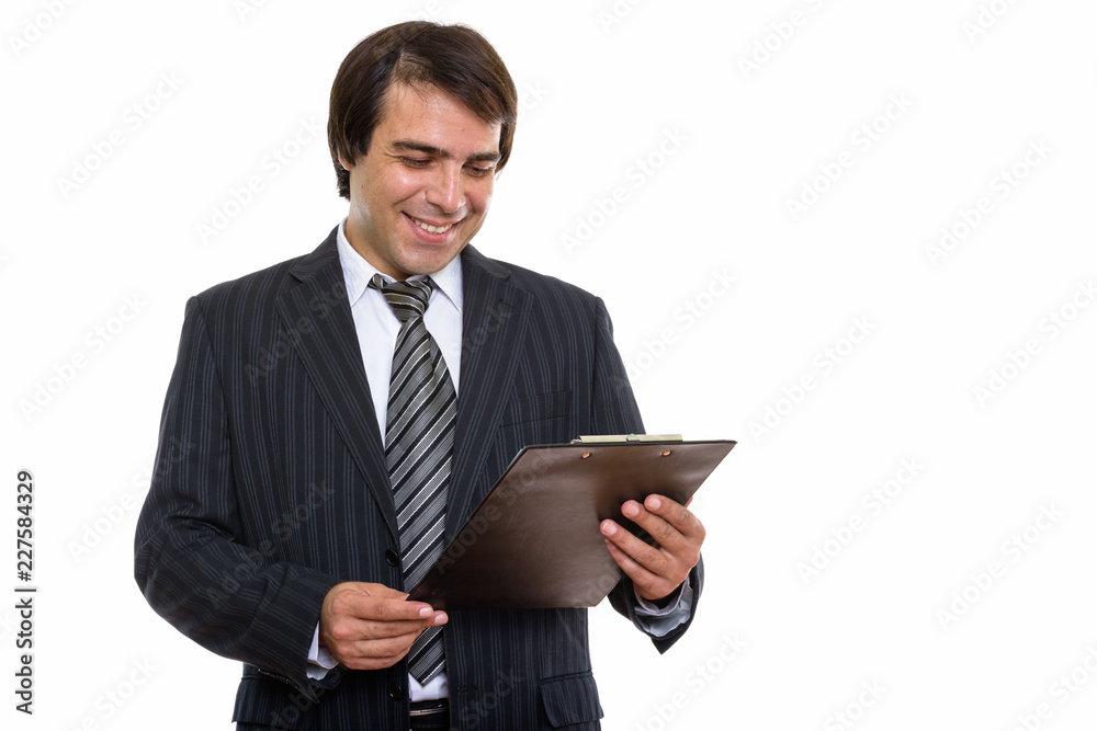 Studio shot of young happy Persian businessman smiling while rea Studio shot of young happy Persian businessman smiling while rea