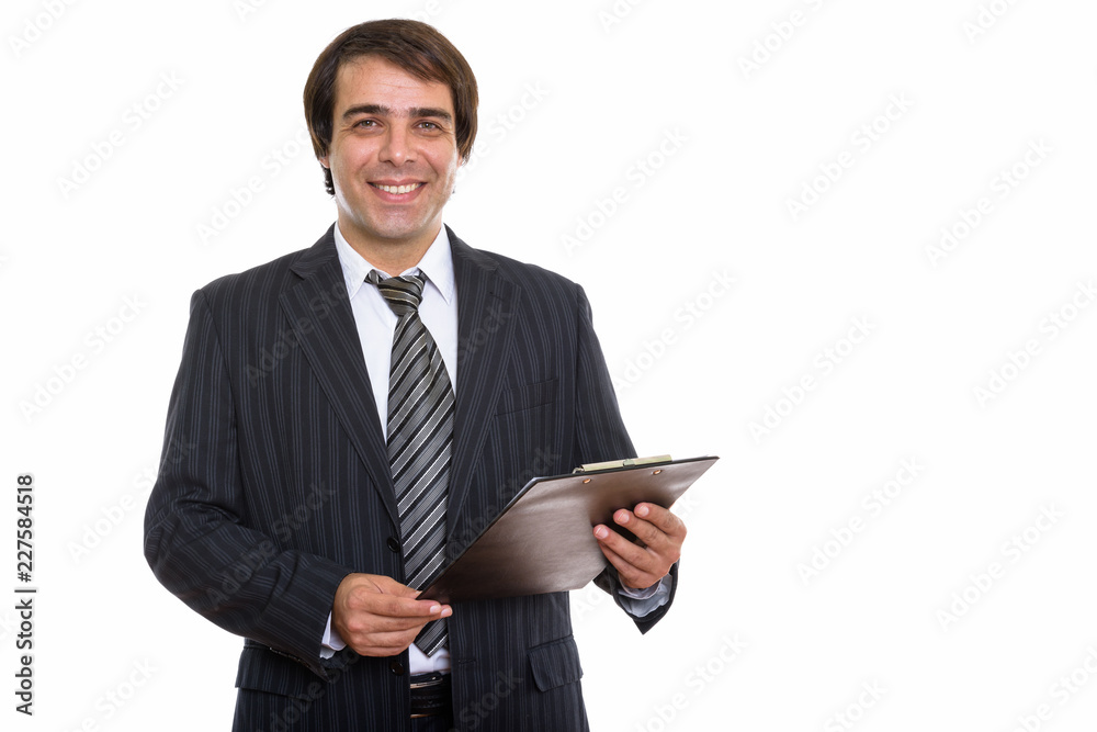 Studio shot of young happy Persian businessman smiling while hol Studio shot of young happy Persian businessman smiling while hol