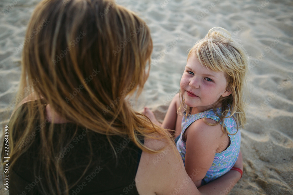 Young mom and daughters enjoying each other on the beach at suns Young mom and daughters enjoying each other on the beach at suns