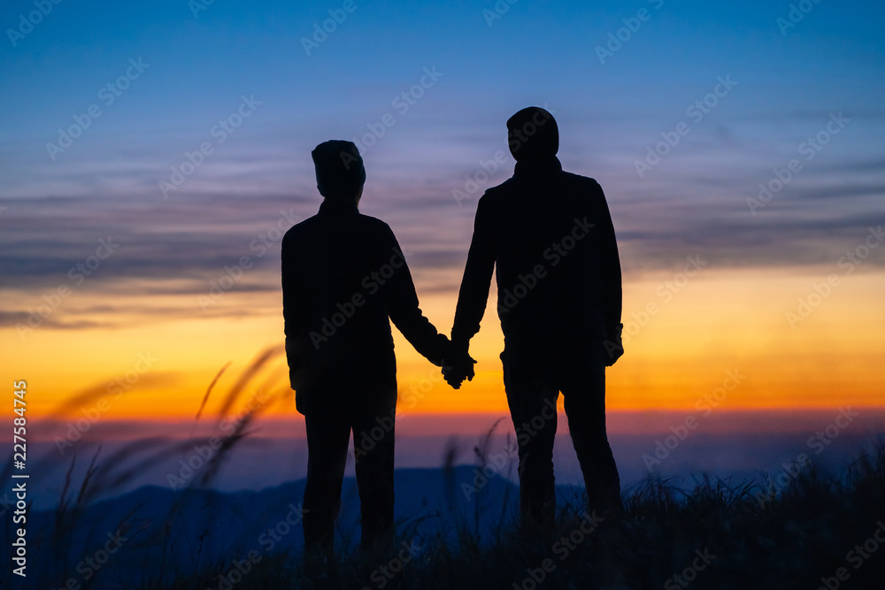 The couple on the mountain enjoying a picturesque sunrise background