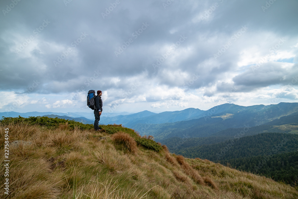 The man standing on the mountain on the rainy cloud background