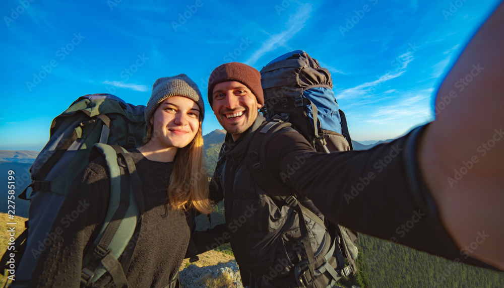 The happy couple taking a selfie on the mountain background