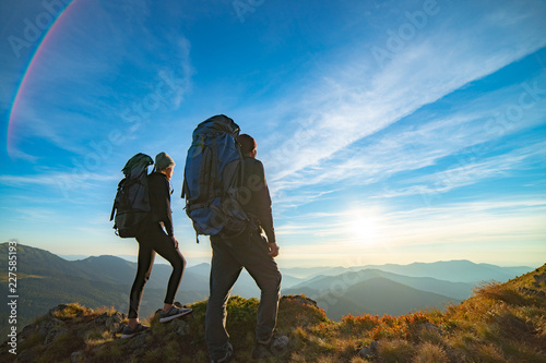 The couple standing on the mountain with a picturesque sunrise background