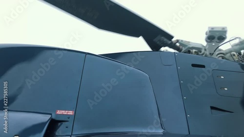 View looking up at the upper section of a helicopter, tail rotor and main rotors spinning photo