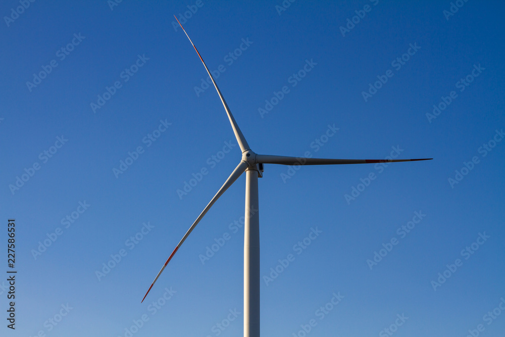 Windmill for electric power production on blue sky background. Sunset, closeup Windmill for electric power production on blue sky background. Sunset, closeup