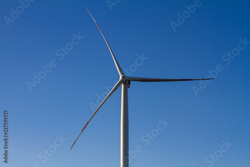 Windmill for electric power production on blue sky background. Sunset, closeup