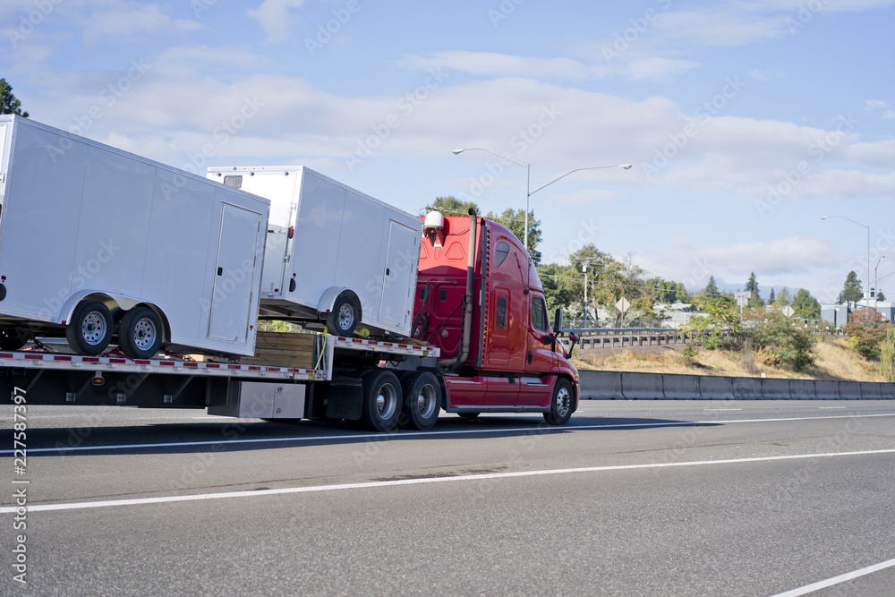 Red big rig semi truck transporting trailers on step down semi trailer