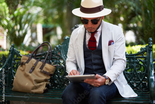 Man with hat and tie on a bench