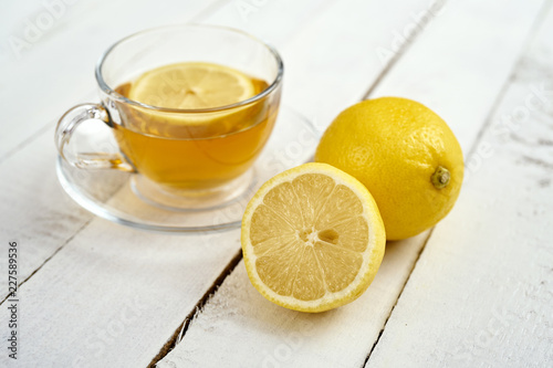 delicious hot tea with honey and two lemons on an old white wooden table