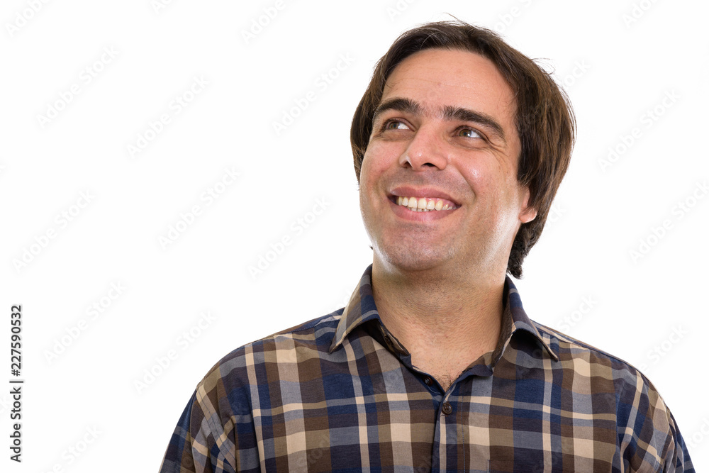 Studio shot of young happy Persian man smiling and thinking whil