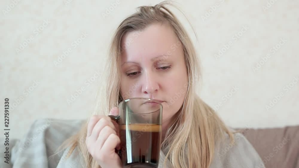Woman with a cold, flu, drink warm tea with lemon. She is sick, fever, chills Woman with a cold, flu, drink warm tea with lemon. She is sick, fever, chills