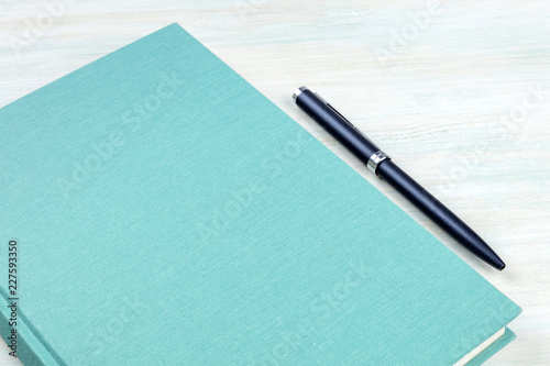 A photo of a teal blue journal with a pen, an elegant notebook or planner with copy space