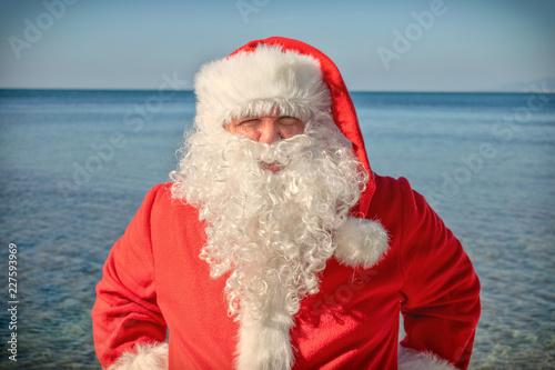 Santa's vacation at sea. Traditional red outfit and relaxing on the beach © Dmitry_Tkachev