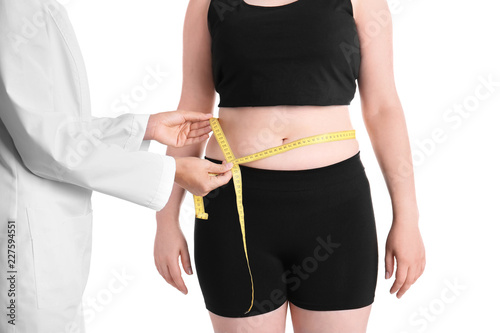 Doctor measuring waist of overweight woman before weight loss on white background