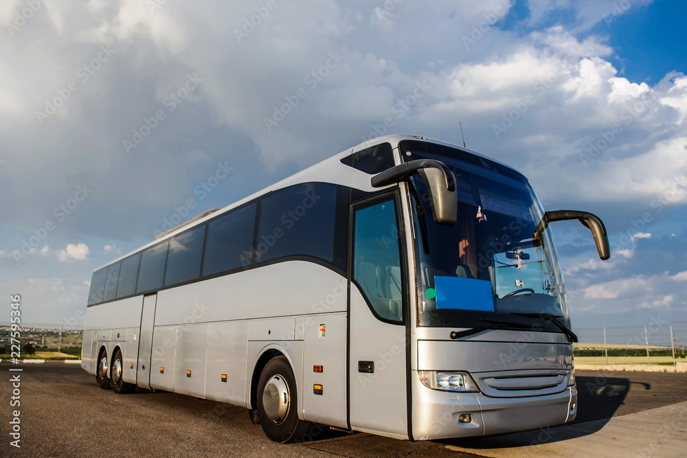 Bus staying in the parking lot under a blue sky with clouds