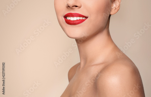 Beautiful young woman with red lips on color background, closeup. Space for text