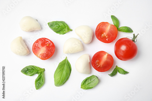 Fresh green basil leaves, cherry tomatoes and mozzarella on white background, top view