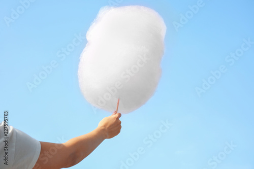 Woman holding cotton candy against blue sky