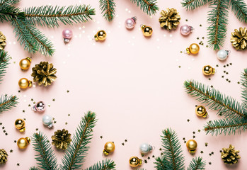 Pastel Pink Christmas Festive frame of fir branches, golden balls and confetti