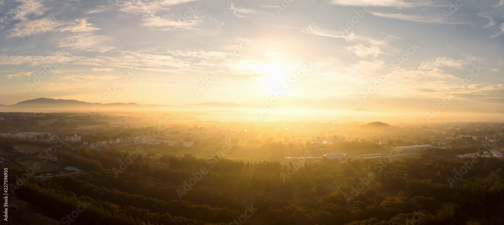 Aerial view of golden sunlight at sunrise with fog covered city town at the summer seasons.