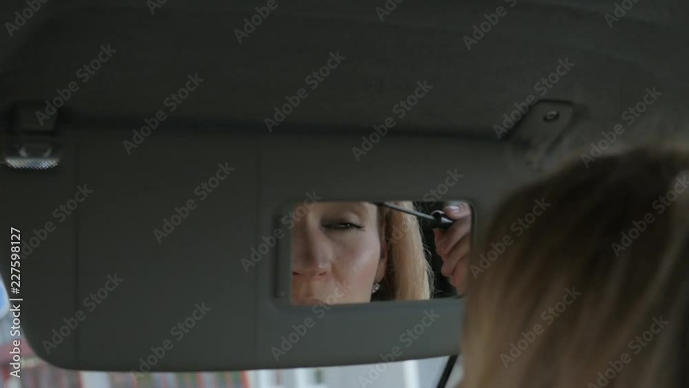 Young glamorous woman paints eyebrows in a car looking to rearview mirror. slow motion Young glamorous woman paints eyebrows in a car looking to rearview mirror. slow motion