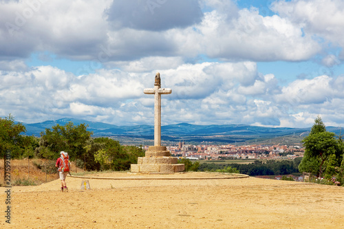 Camino de Santiago (Spain) - The Santo Toribio stone cross and a pilgrim walking along the way of St.James, near Astorga photo