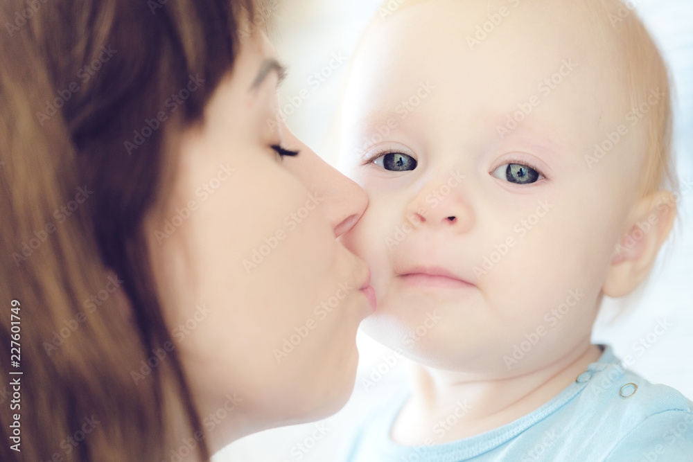 Portrait of beautiful mother kissing her child girl