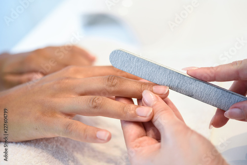 Foto Woman in a nails salon receiving a manicure with nail file