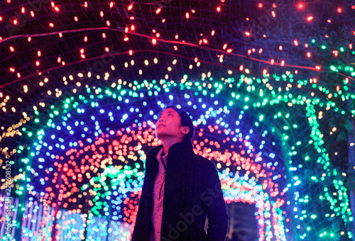 Young fashionable asian woman looking up at colorful rainbow lights