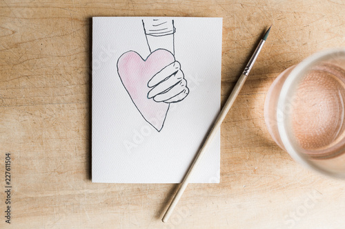 illustrated hand holding a watercolored heart photo