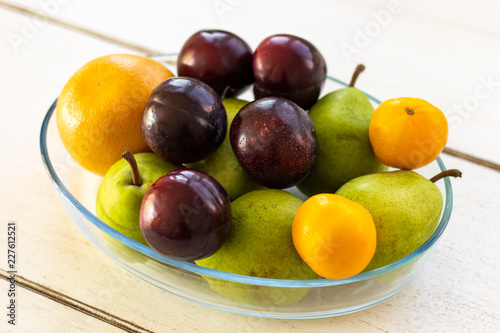 Fresh fruit in a bowl lying on a wooden table from a side view
