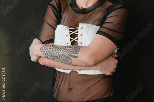 Woman with tattoed arm wearing corsete photo