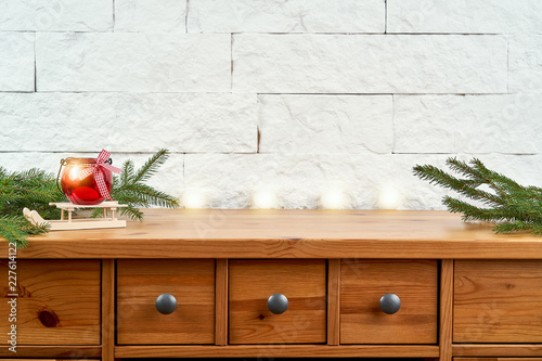 Christmas decoration with twigs of spruce and a red lantern on an old shelf on the background of a white brick wall