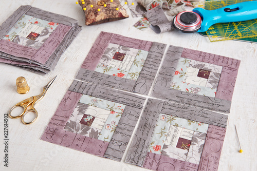 Patchwork log cabin blocks, stack of blocks, sewing accessories on white wooden surface