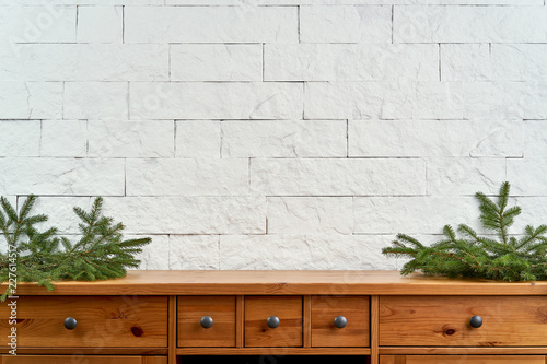 Christmas decoration with blank space with twigs of spruce on an old shelf on the background of a white brick wall