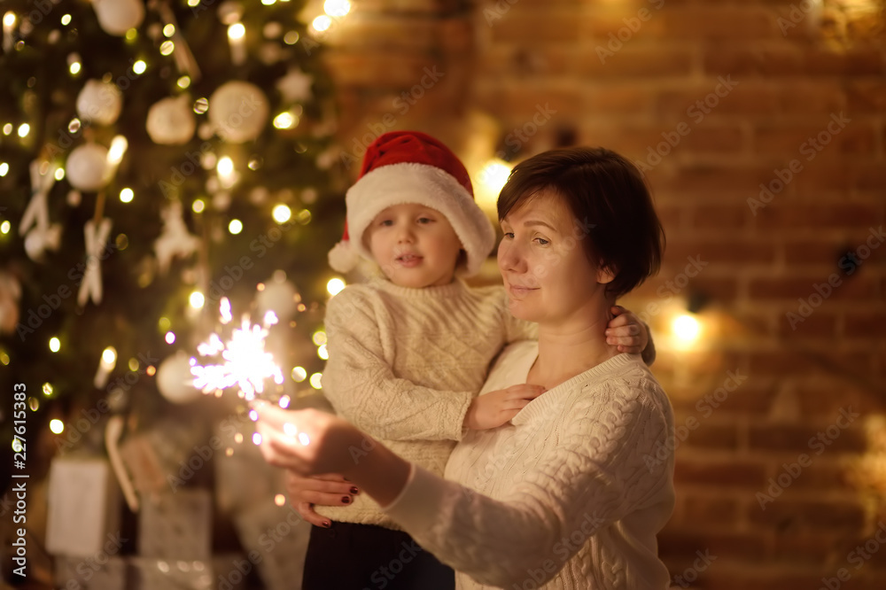 Mother or grandmother with her little son or grandson celebration Christmas with sparkler