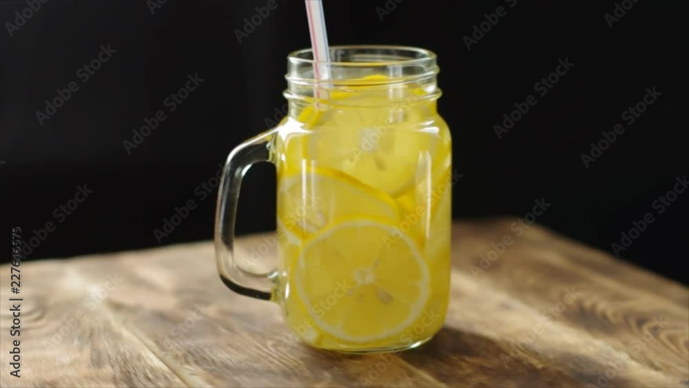 Freshly made lemonade with lemon in the Bank. Dark wooden background, selective focus. Freshly made lemonade with lemon in the Bank. Dark wooden background, selective focus.
