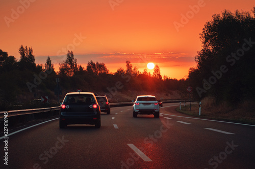 Driving in a urban road in the city at colorful orange sunrise morning