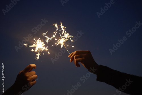 Friends holding sparklers up to the night sky