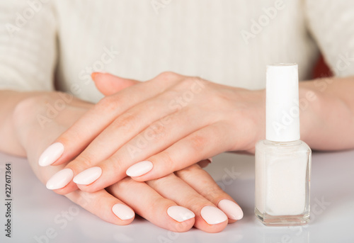  woman s hands with white nail varnish bottles