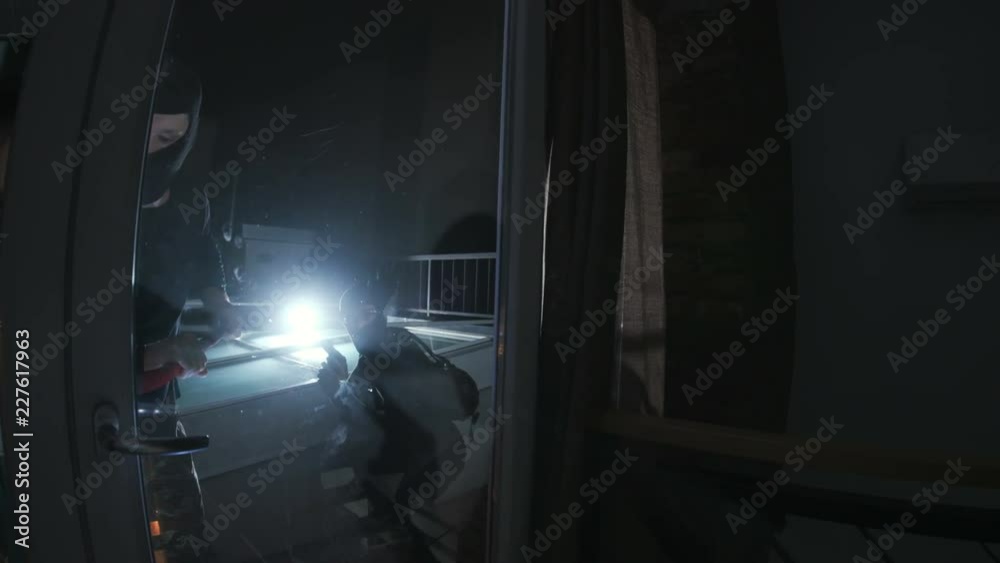 Thieves with gun picking lock and getting into apartment for commit crime. Two men with scrap and gun. Darkness. Night time. Masked men. Thieves with gun picking lock and getting into apartment for commit crime. Two men with scrap and gun. Darkness. Night time. Masked men.