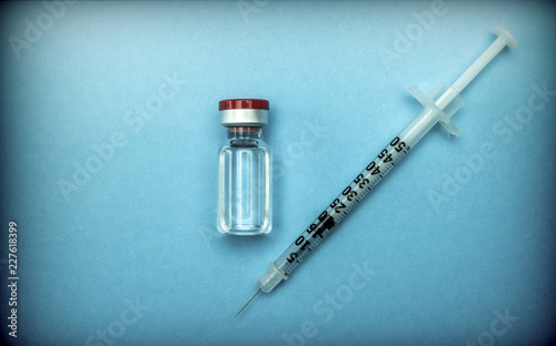 Antibiotic Vial with an isolated syringe on a blue background, conceptual image photo