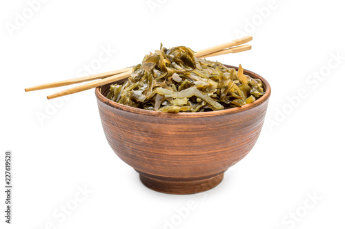 Bowl with seaweed and chopsticks on white. Close up.