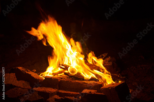 fire with sparks on a black background with elements of firewood coal and baked bricks.