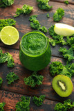 Green smoothies with kale, kiwi, apple and lime on wooden table
