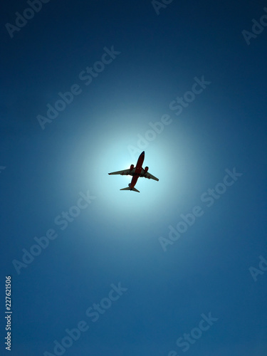 Airplane on a blue sky with sun in the background