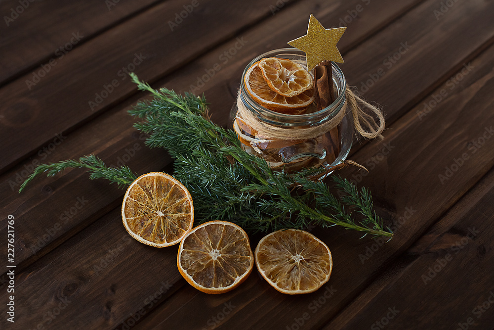 dried orange slices in a jar with a branch of a Christmas tree on a wooden background with gold star decoration dried orange slices in a jar with a branch of a Christmas tree on a wooden background with gold star decoration