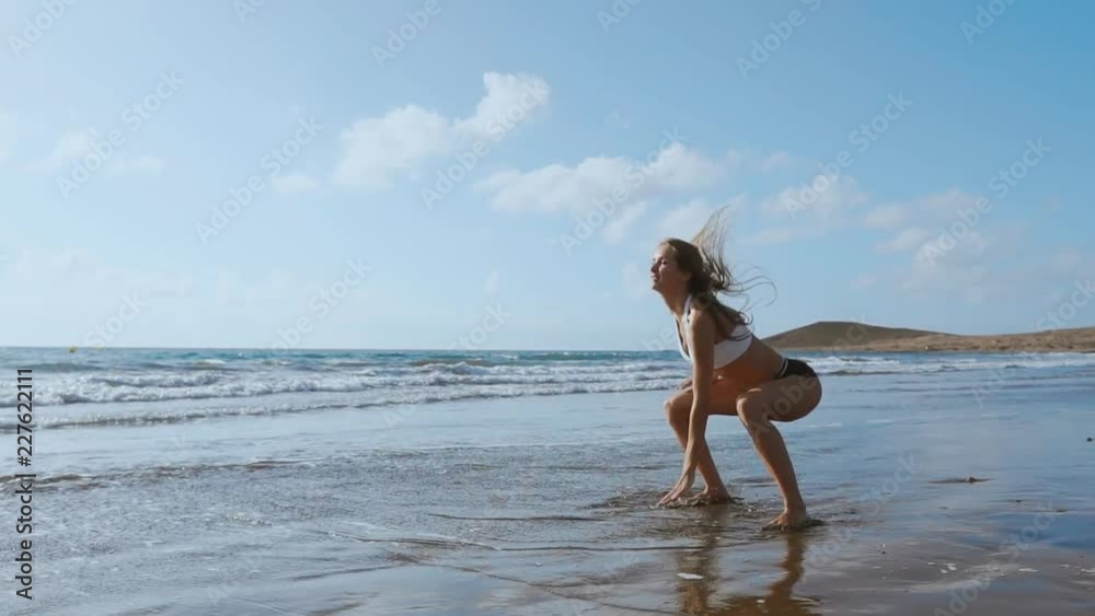 Young strong woman in sportswear doing plyometric exercises on pier. Jump squats, fitness workout outdoors. SLOW MOTION STEADICAM