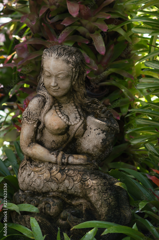 Harmony sculpture, thailand national park green leaves and flowers. Vertical.